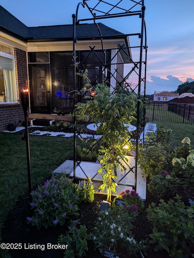 exterior space with brick siding, a sunroom, a yard, and fence