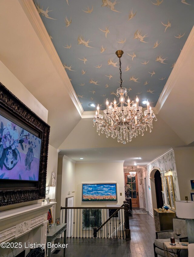 interior space with arched walkways, an upstairs landing, a raised ceiling, and crown molding