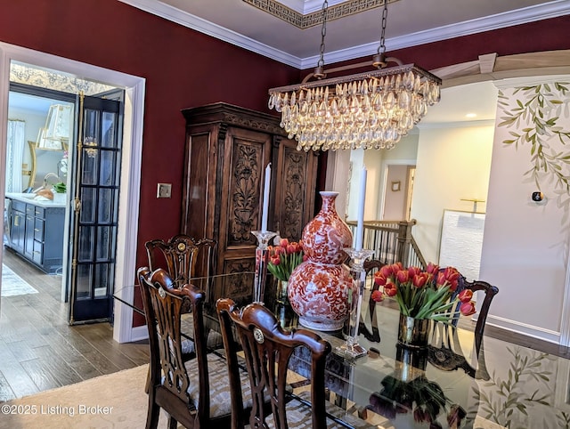 dining room featuring an inviting chandelier, crown molding, dark wood-style flooring, and baseboards