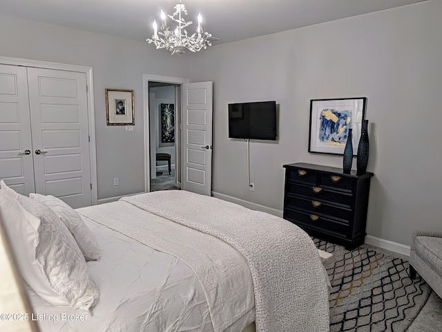 bedroom with a closet, a chandelier, baseboards, and carpet floors