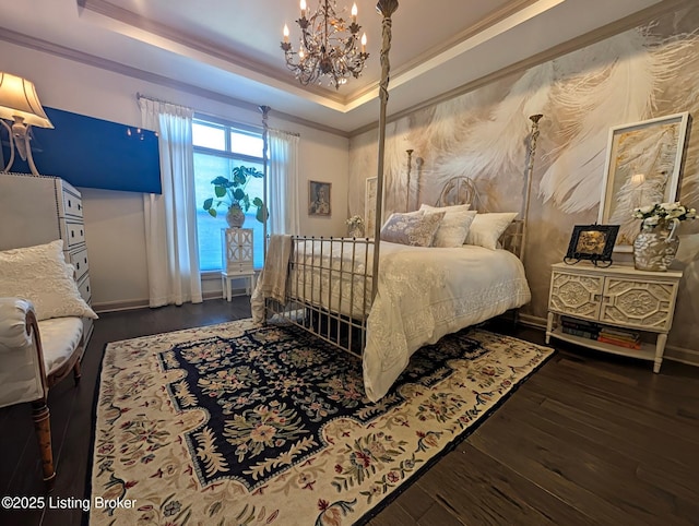 bedroom with wood finished floors, baseboards, a tray ceiling, crown molding, and a notable chandelier