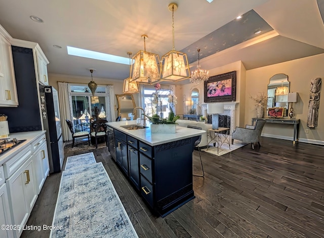 kitchen with light countertops, white cabinets, freestanding refrigerator, and a sink