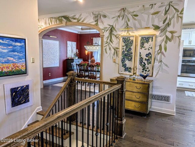 staircase featuring arched walkways, visible vents, crown molding, and wood finished floors