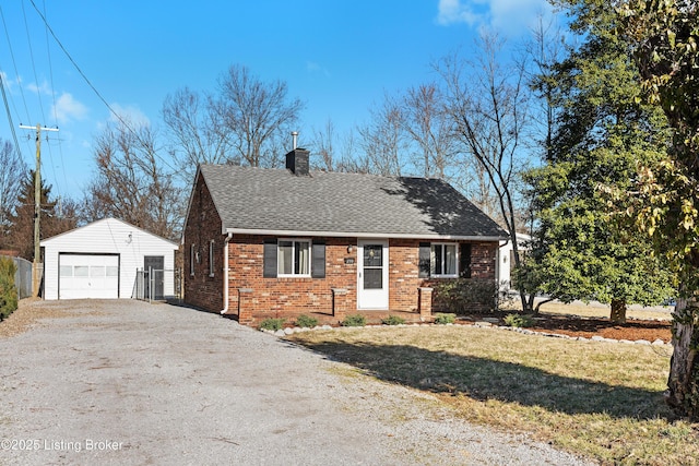 view of front of house featuring brick siding, roof with shingles, a chimney, an outdoor structure, and driveway