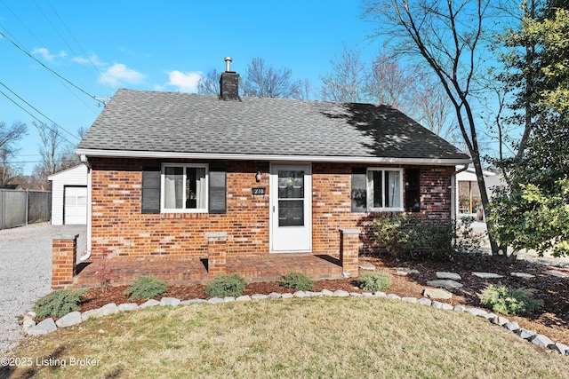 view of front facade featuring brick siding, a shingled roof, fence, a front lawn, and a chimney