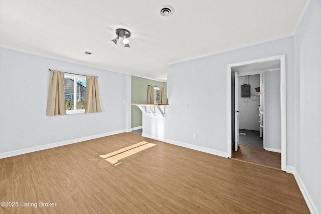 empty room featuring electric panel, wood finished floors, visible vents, and baseboards