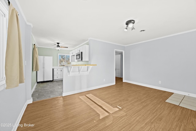 unfurnished living room featuring ornamental molding, light wood-type flooring, a ceiling fan, and baseboards