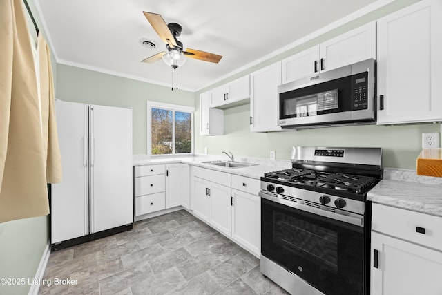 kitchen featuring appliances with stainless steel finishes, white cabinets, a sink, and ornamental molding