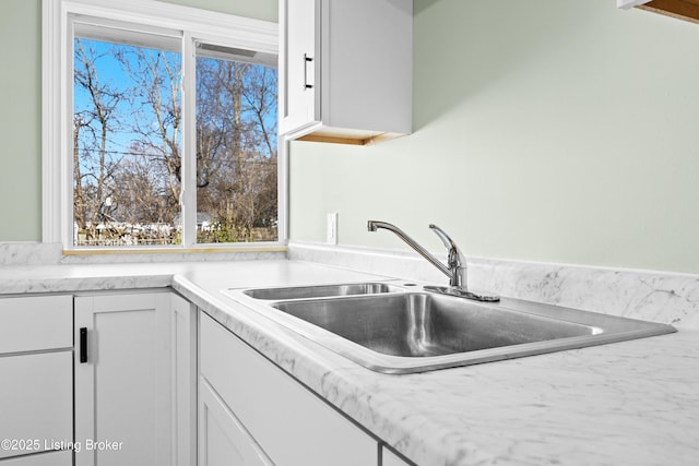 kitchen featuring light countertops, white cabinetry, and a sink