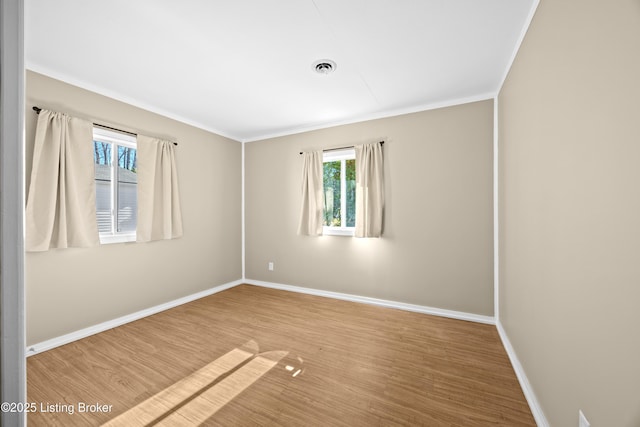 spare room featuring visible vents, crown molding, baseboards, and wood finished floors