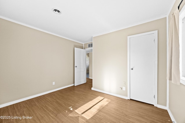 unfurnished bedroom featuring baseboards, crown molding, visible vents, and wood finished floors