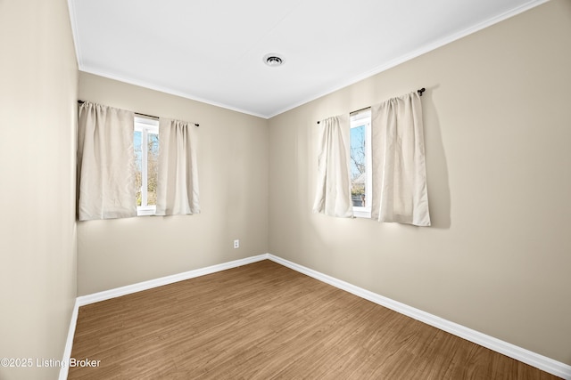 unfurnished room featuring crown molding, wood finished floors, and baseboards