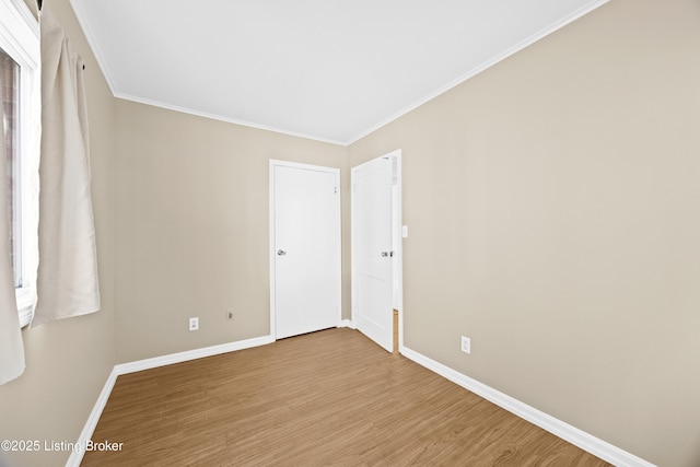 spare room with crown molding, baseboards, and wood finished floors