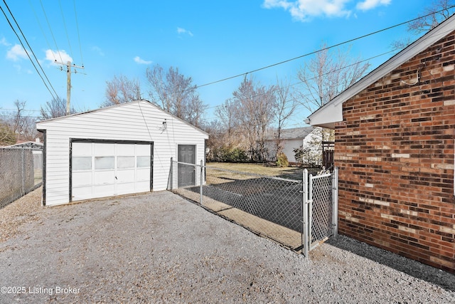 detached garage with driveway, a gate, and fence