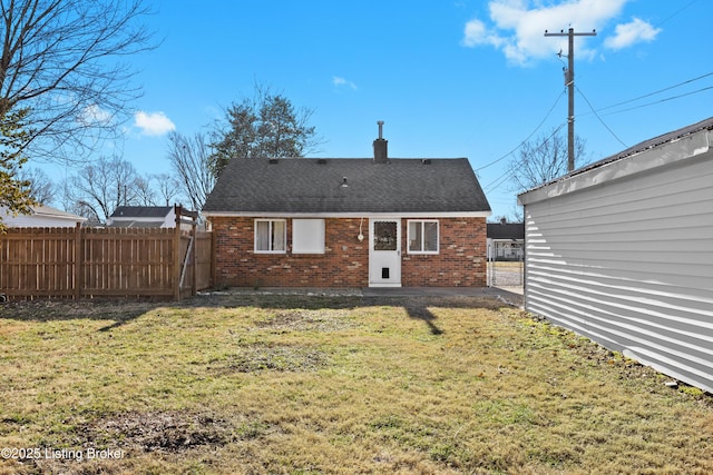 rear view of property featuring brick siding, a lawn, a chimney, and fence