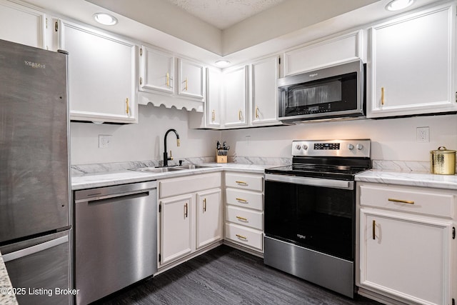 kitchen with appliances with stainless steel finishes, white cabinets, a sink, and dark wood-type flooring