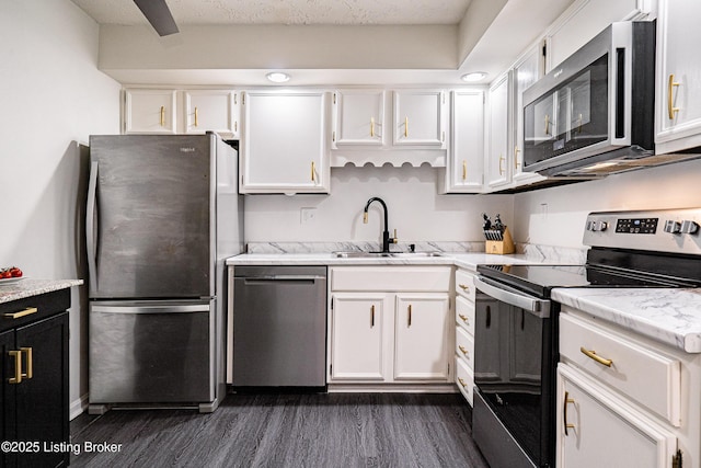 kitchen with stainless steel appliances, white cabinetry, a sink, and dark wood-style floors