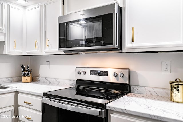 kitchen featuring stainless steel appliances, white cabinets, and light stone counters