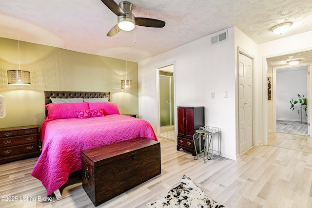 bedroom with visible vents, ceiling fan, a textured ceiling, wood finished floors, and baseboards