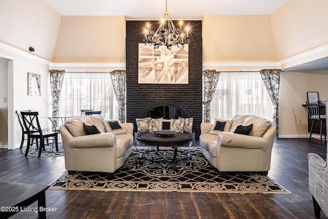 living area featuring a fireplace, a towering ceiling, an inviting chandelier, and wood finished floors