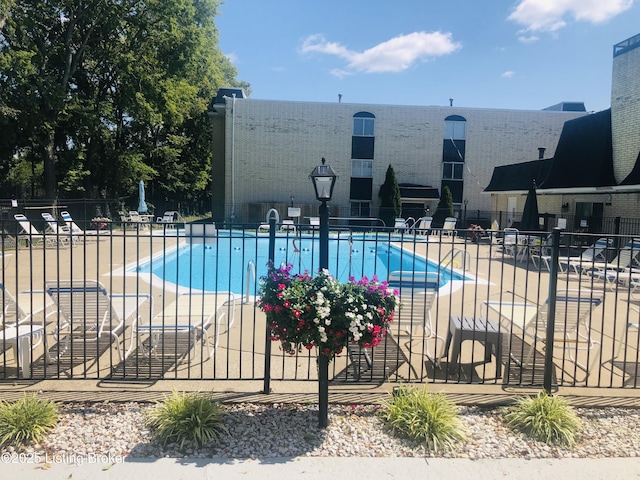 pool with a patio area and fence