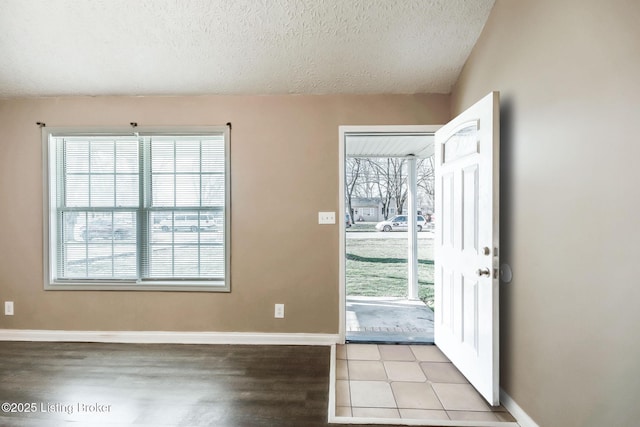 doorway to outside with a textured ceiling, light wood-style floors, and baseboards