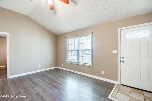 entryway featuring lofted ceiling, a textured ceiling, baseboards, and wood finished floors