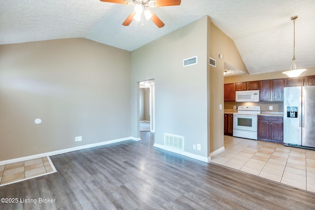 kitchen featuring white appliances, light wood-style flooring, visible vents, and vaulted ceiling