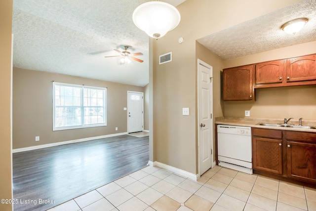 kitchen featuring visible vents, a ceiling fan, white dishwasher, a textured ceiling, and a sink