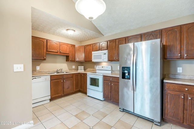 kitchen featuring light tile patterned floors, light countertops, a sink, a textured ceiling, and white appliances