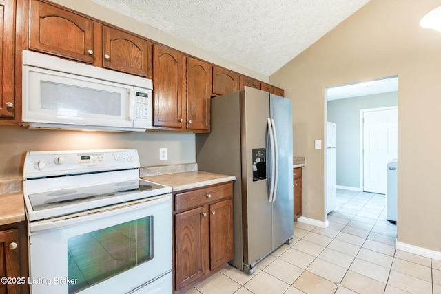 kitchen featuring brown cabinets, lofted ceiling, white appliances, and light countertops