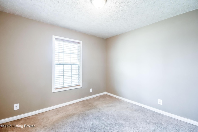 unfurnished room with a textured ceiling, carpet floors, and baseboards