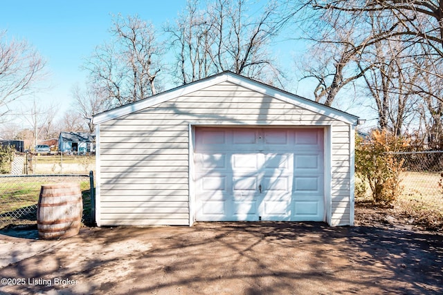 detached garage featuring fence and driveway