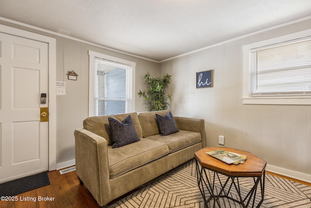 living room with ornamental molding, baseboards, visible vents, and hardwood / wood-style floors