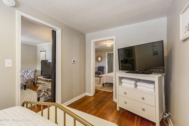 bedroom with a textured ceiling, wood-type flooring, and baseboards