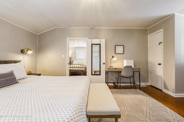 bedroom featuring lofted ceiling, baseboards, and wood finished floors