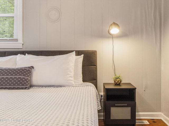 bedroom with baseboards, visible vents, and wood finished floors