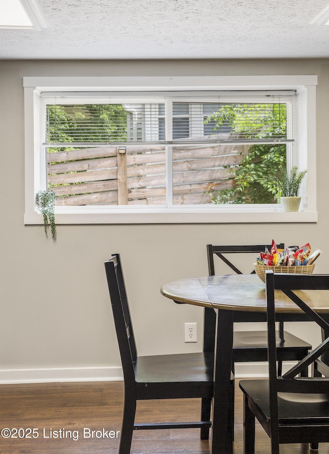 dining space featuring a textured ceiling, baseboards, and wood finished floors