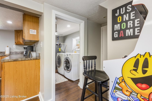 clothes washing area with a textured ceiling, recessed lighting, laundry area, dark wood-type flooring, and washing machine and clothes dryer