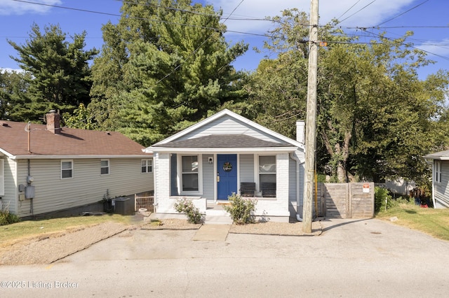 bungalow with a porch, brick siding, and central AC