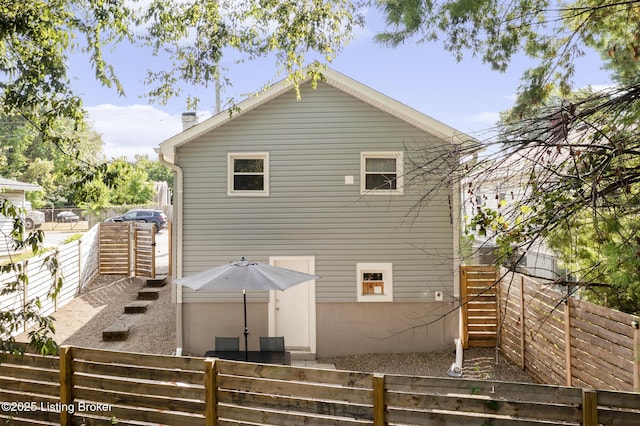 rear view of property featuring a fenced backyard and stairway