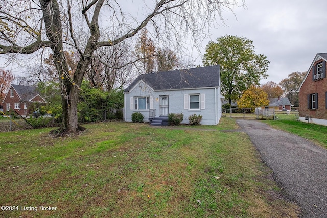 bungalow-style house with brick siding, roof with shingles, a front yard, and fence