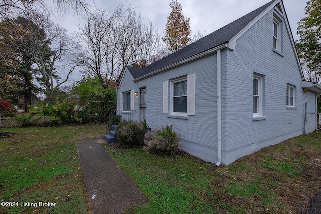 view of property exterior featuring brick siding and a lawn