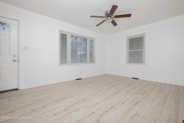 spare room with visible vents, ceiling fan, light wood-style flooring, and baseboards