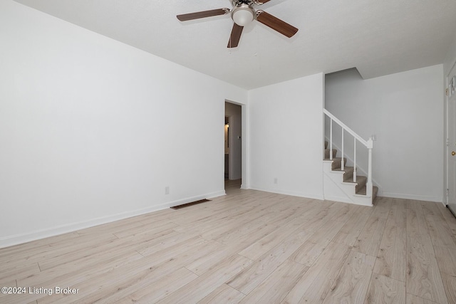 unfurnished room with light wood finished floors, visible vents, baseboards, a ceiling fan, and stairway