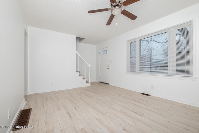 unfurnished living room featuring stairway, baseboards, visible vents, and light wood-style floors