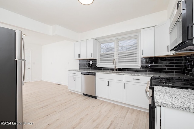 kitchen featuring decorative backsplash, appliances with stainless steel finishes, light wood-style floors, white cabinetry, and a sink