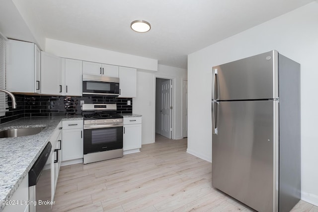 kitchen featuring decorative backsplash, light wood-style flooring, stainless steel appliances, white cabinetry, and a sink