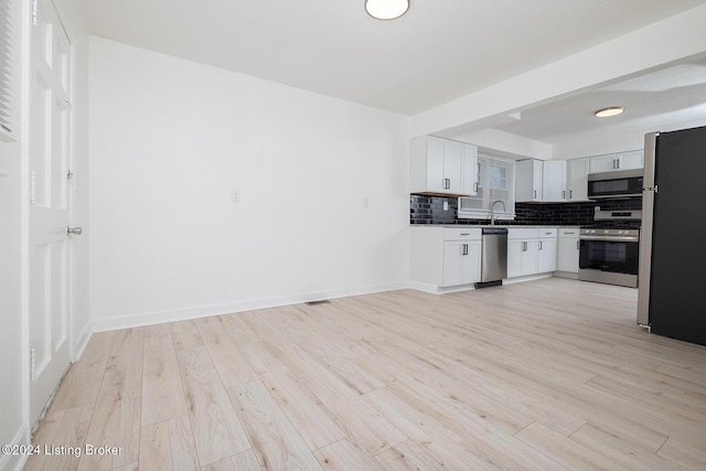 kitchen featuring light wood finished floors, tasteful backsplash, appliances with stainless steel finishes, and baseboards