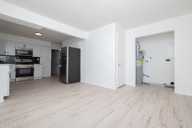 kitchen with stainless steel appliances, tasteful backsplash, light countertops, light wood-style floors, and electric water heater